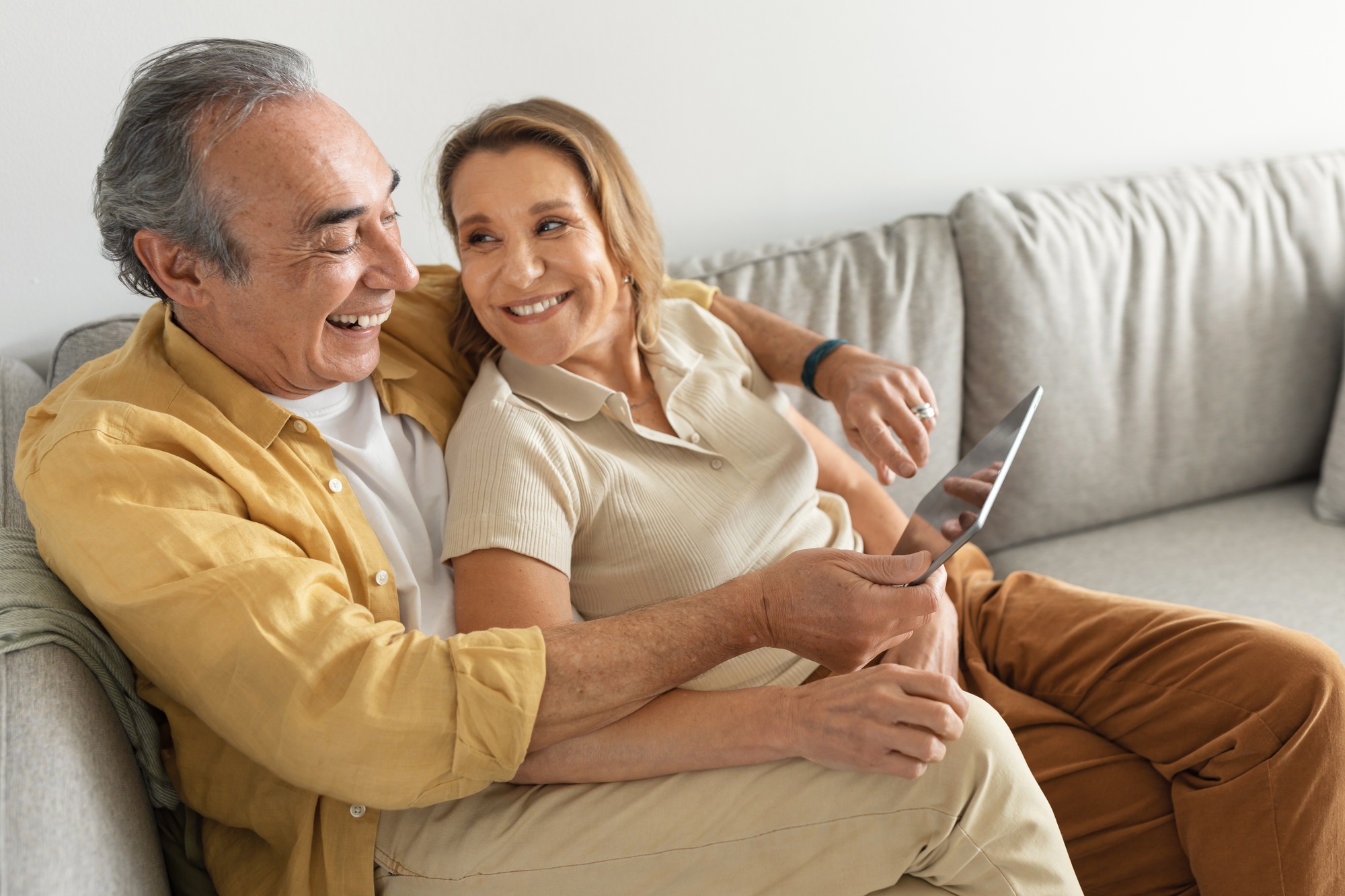 Happy senior married couple enjoying digital gadget world using tablet computer, websurfing or